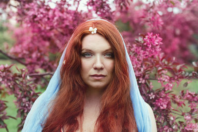 Portrait of young woman standing against trees