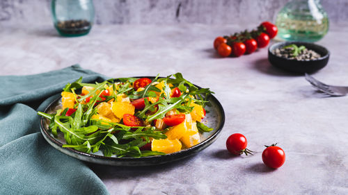 Homemade salad of orange, cherry tomatoes and arugula on a plate web banner