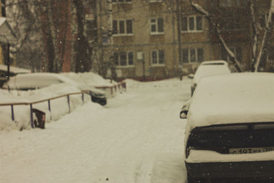 Snow covered road amidst buildings in city during winter