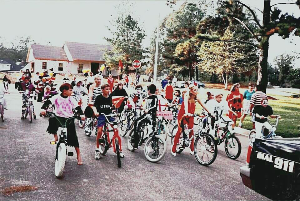 PEOPLE RIDING BICYCLES ON ROAD AGAINST BUILDINGS