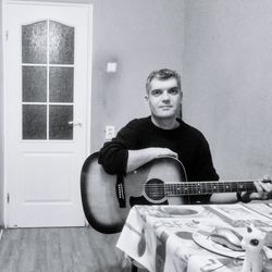 Portrait of man playing guitar at home