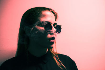 Close-up of young woman against red background