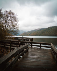 Wooden bridge over lake against sky