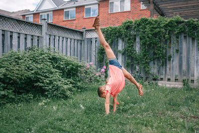 Full length of girl doing handstand in yard