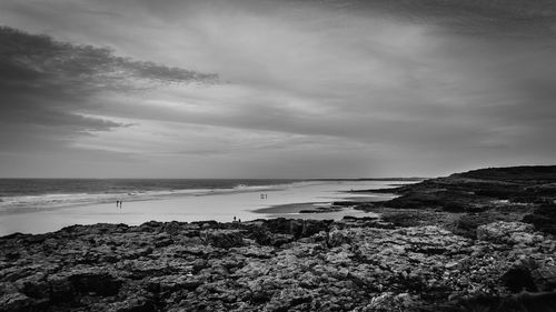 View of calm beach against cloudy sky