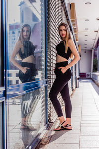 Side view of beautiful young woman standing on sidewalk in city