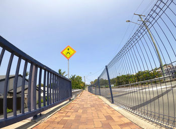 Road sign on bridge against sky