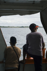 Rear view of men on sea against sky