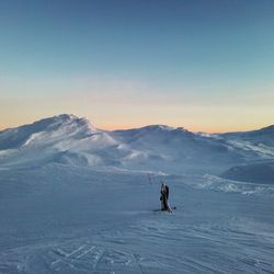 People on snowcapped mountain against clear sky