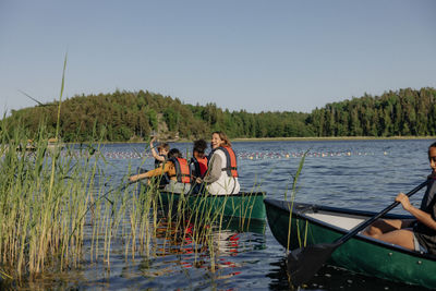 Happy children enjoying while doing kayaking on lake at summer camp