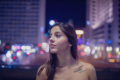 Young woman looking away at illuminated city