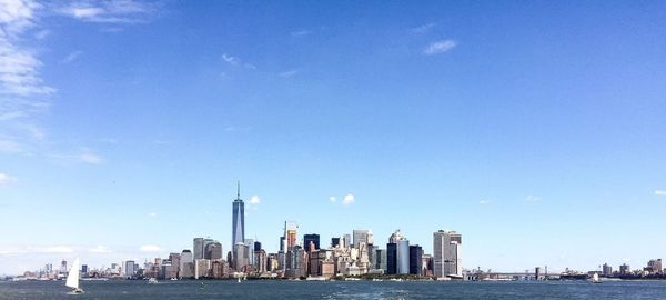 City at waterfront against blue sky