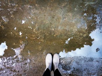 Low section of person standing on puddle