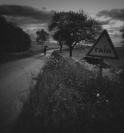 Road sign against cloudy sky