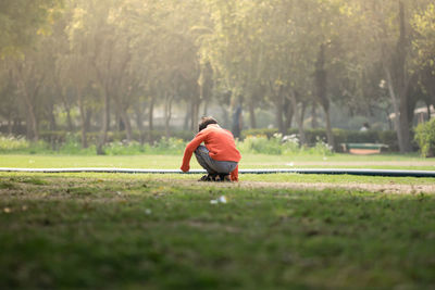 Rear view of boy crouching on grassy land in park