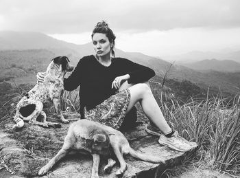 Portrait of woman with dog sitting on mountain against sky