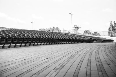 Empty benches on footpath in city against sky