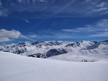 Scenic view of snowcapped landscape by mountains against blue sky