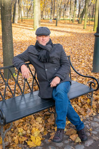 Portrait of man sitting on bench in park