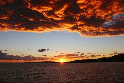 Scenic view of sea against dramatic sky during sunset