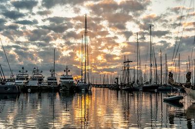 Sailboats moored at harbor during sunset