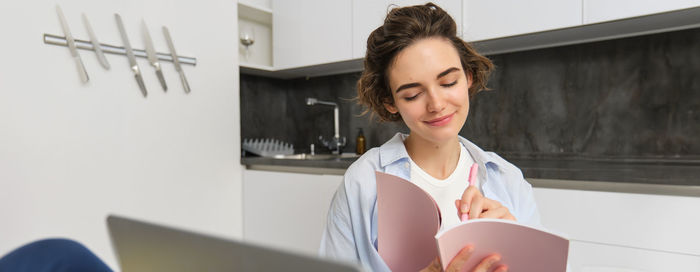 Portrait of young woman using mobile phone at home