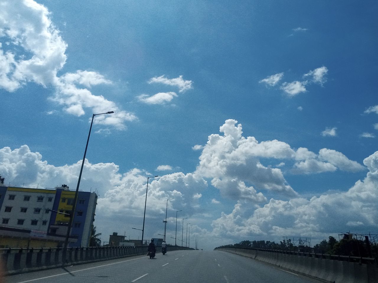 cloud, sky, transportation, road, highway, street, city, nature, the way forward, horizon, sign, mode of transportation, architecture, freeway, car, symbol, motor vehicle, road marking, marking, no people, day, travel, built structure, diminishing perspective, outdoors, blue, infrastructure, vanishing point, street light, lane, travel destinations, building exterior, road sign