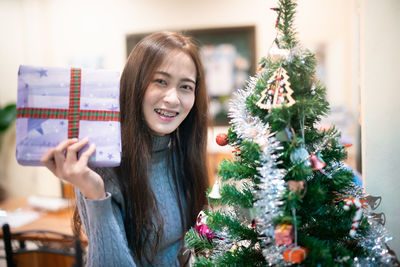 Portrait of happy young woman with christmas tree