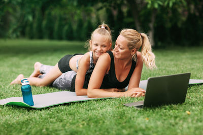 Mother and girl using laptop on grass