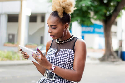 Young businesswoman consulting her tablet standing by the roadside.