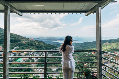 Woman standing by railing against mountains