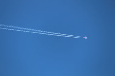 Low angle view of airplane flying against clear blue sky