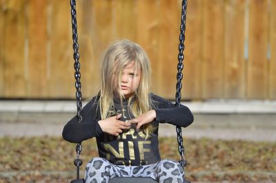 Portrait of cute girl sitting on swing in playground