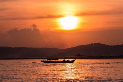 Silhouette boat in sea against orange sky