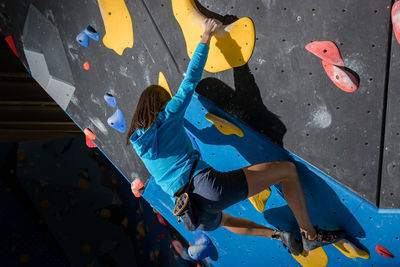 Athletic girl climbing on an indoor climbing wall