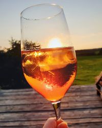 Close-up of wineglass on glass against sunset