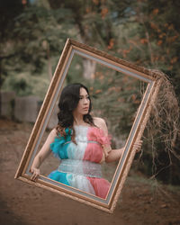 Digital composite image of woman looking away while holding picture frame 