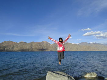 Girl jumping in backdrop of pangong lake  against sky