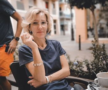 Mid adult woman holding coffee while sitting outdoors