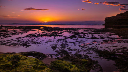 A colourful sunset taking place along a rocky coast line.