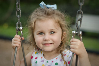 Portrait of smiling girl sitting on swing