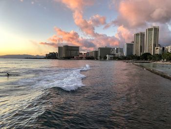 Panoramic view of sea and buildings against sky during sunset