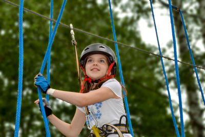 Adventure climbing high wire park - people on course in mountain helmet and safety equipment.