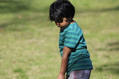 Side view of boy standing on grassy field