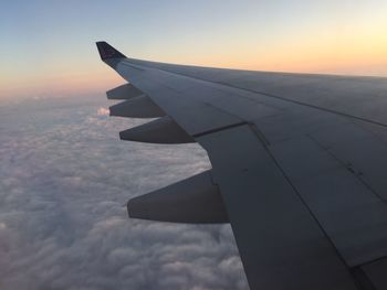 Cropped image of airplane flying in sky during sunset