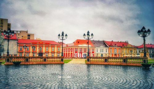 Buildings by river against sky in city