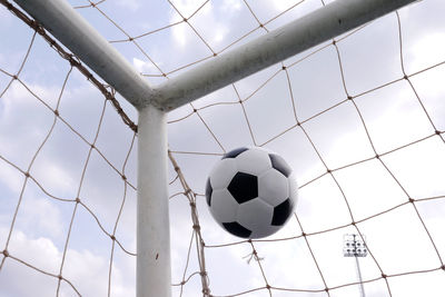 Low angle view of soccer ball on net against sky