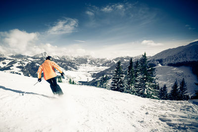 Man skiing on snowcapped mountain against sky
