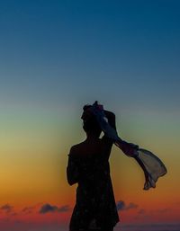 Low angle view of silhouette woman standing against sky during sunset
