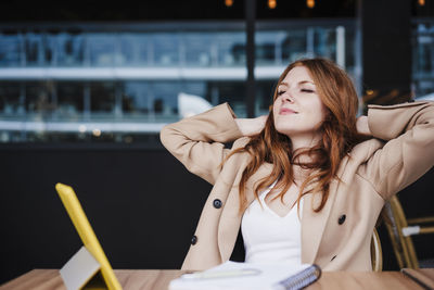 Young woman looking away while sitting on table